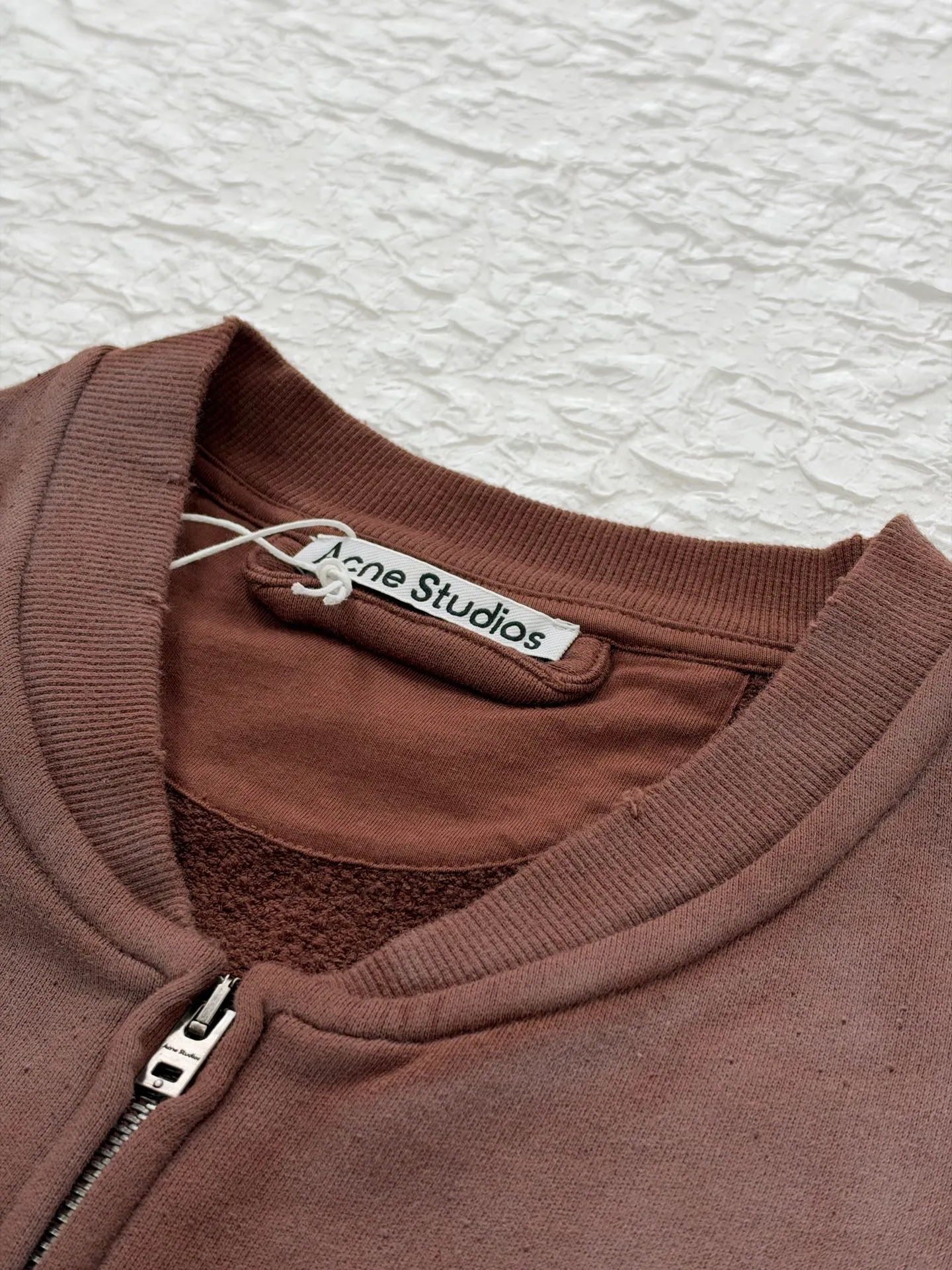 Acne Studio distressed washed zipper baseball sweatshirt is made of 100% cotton terry cloth, garment washed + distressed and sanded. The body adopts dropped shoulder sleeves, a loose oversize silhouette, a V-shaped ribbed baseball collar design, and the edge of the collar is deliberately frayed and damaged. The main zipper is made of distressed metal zipper, and the front panel is positioned with glue crack printing. Size: S/M/L/XL